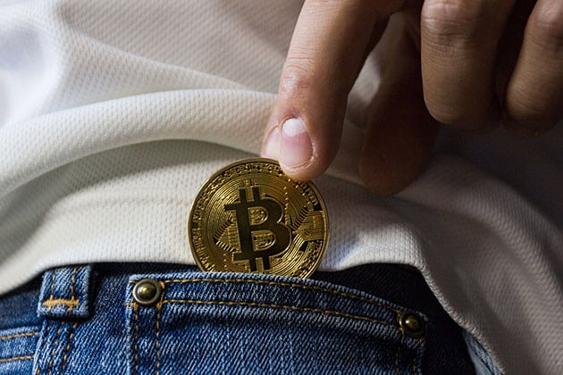 Person putting a bitcoin in their pocket