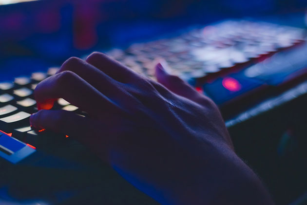 Dark image with persons hand on keyboard navigating dark web