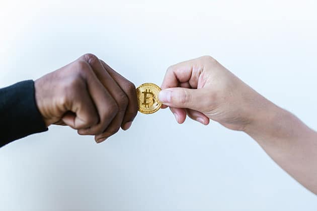 Picture of two holding hands holding a Bitcoin